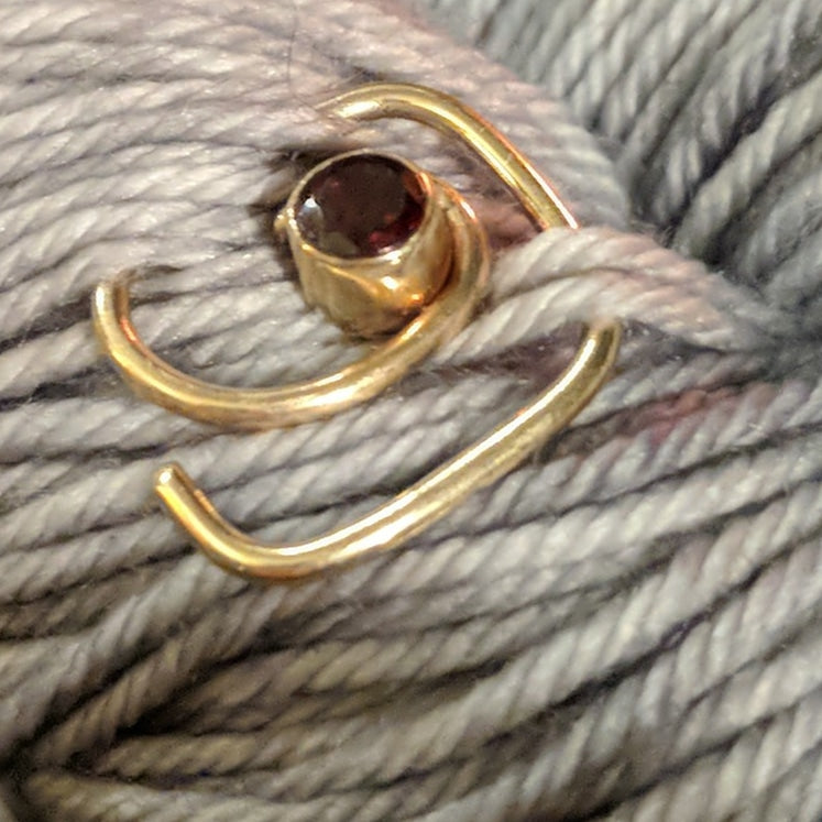 Gold twisty-in-pin, set with a garnet.